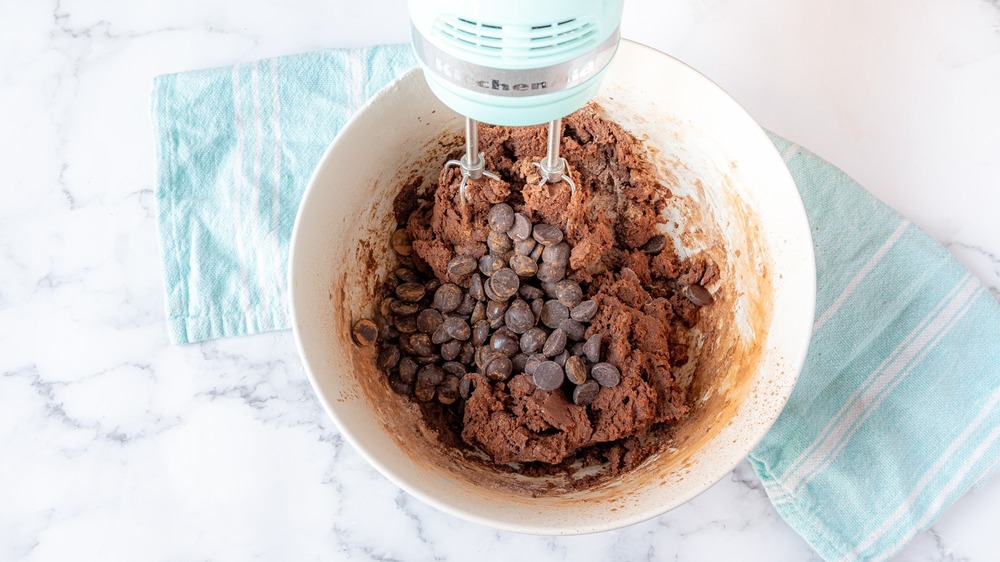 mixing chocolate chips into cookie dough for rich double chocolate chip cookies