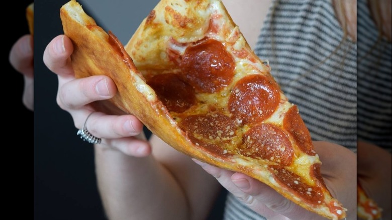 person holding pepperoni pizza