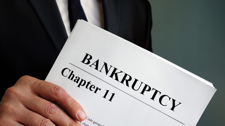 man holding paper that says Bankruptcy chapter 11