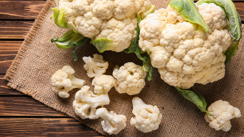 heads and florets of cauliflower on wooden board