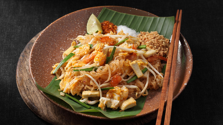 Pad Thai on wooden plate with chopsticks