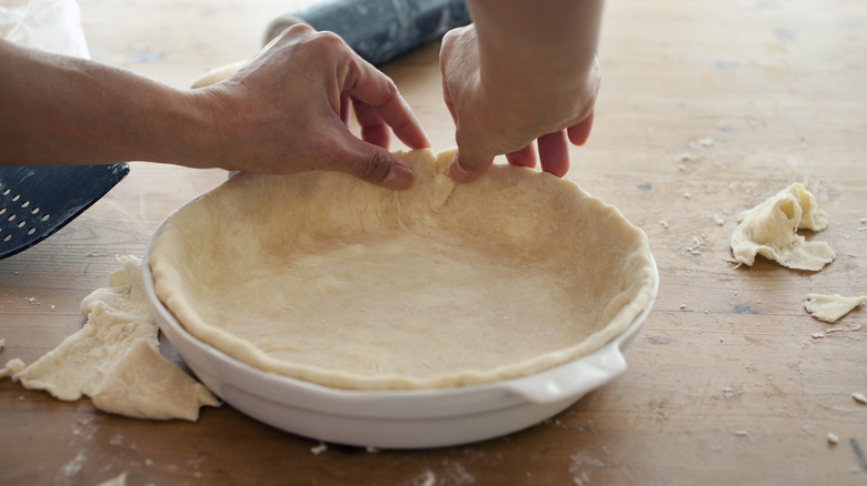 Person pressing pie dough into dish