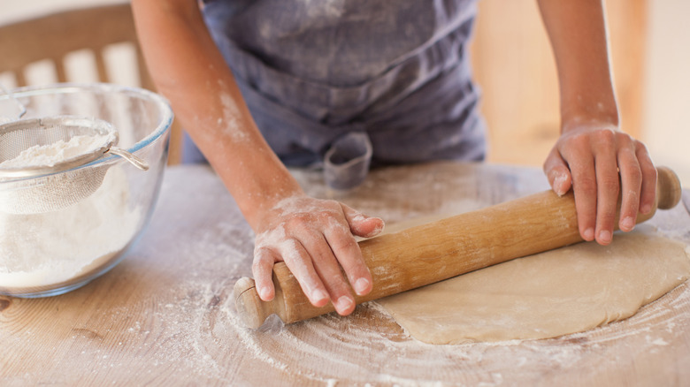 Person rolling out dough with a rolling pin