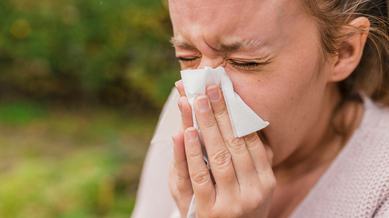 person sneezing into tissue