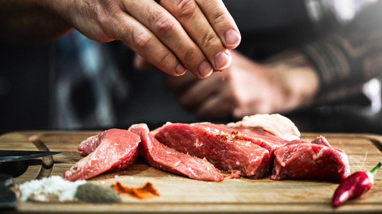 person seasoning a steak