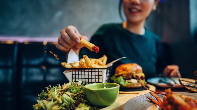 woman eating fries and burger