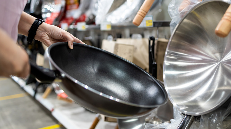 person holding nonstick pan in shopping aisle