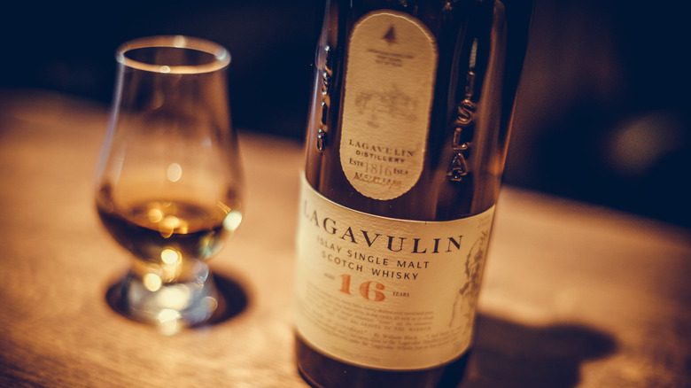 A bottle of Lagavulin scotch next to half-full drinking glass