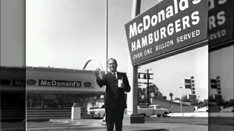 Ray Kroc holding a burger and smiling