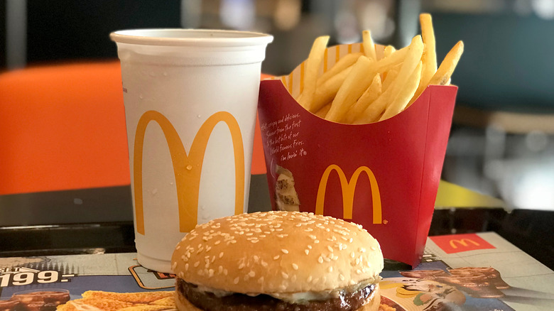 A burger in front of fries and soda