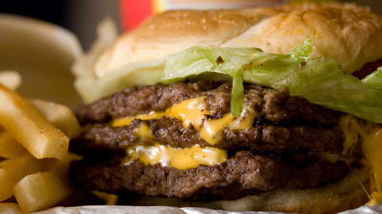 Wendy's triple cheeseburger, beef patties and melted cheese foreground