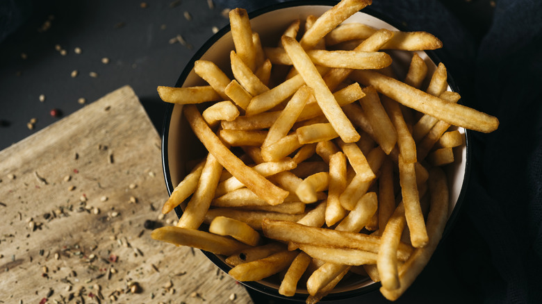 overhead view of crispy french fries on a dark background