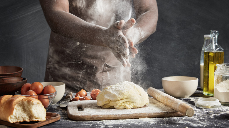 Baker handling bread dough with eggs and oil