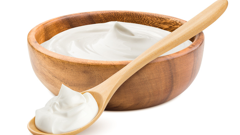 Sour cream in wooden bowl with wooden spoon