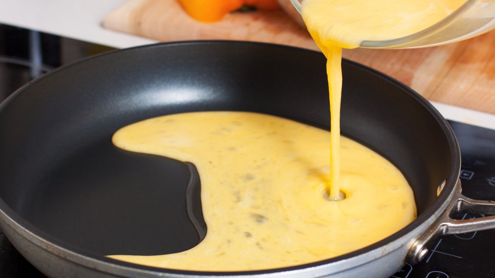 pouring scrambled eggs into a pan