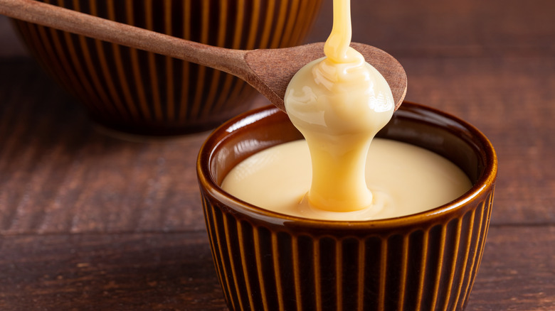 Pouring sweetened condensed milk into ramekin