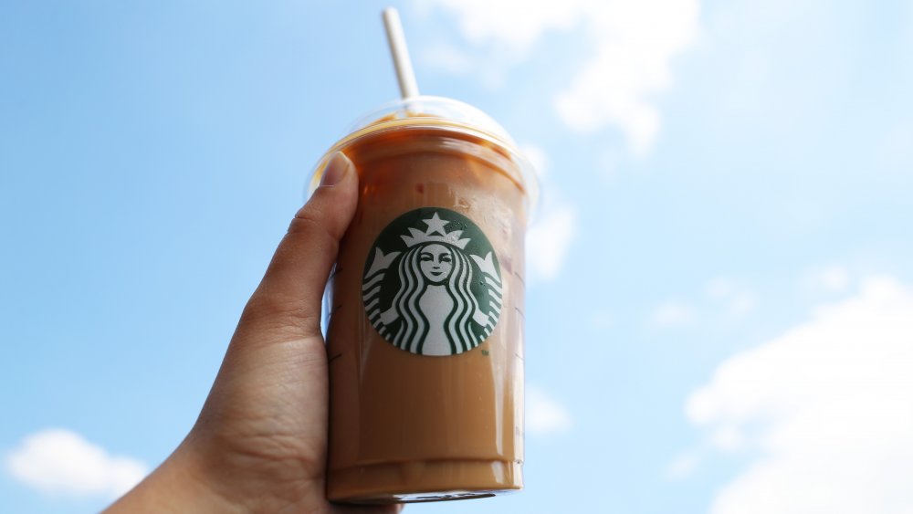 hand holding starbucks drink up to the sky