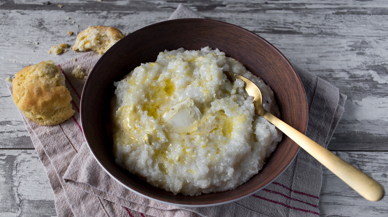 bowl of buttered grits with biscuit