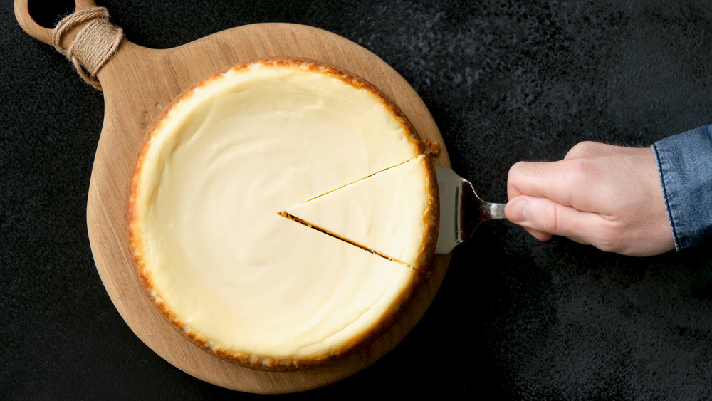 Person removing a cheesecake slice