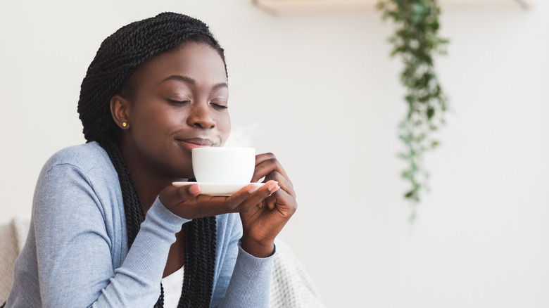 woman smelling a cup of coffee