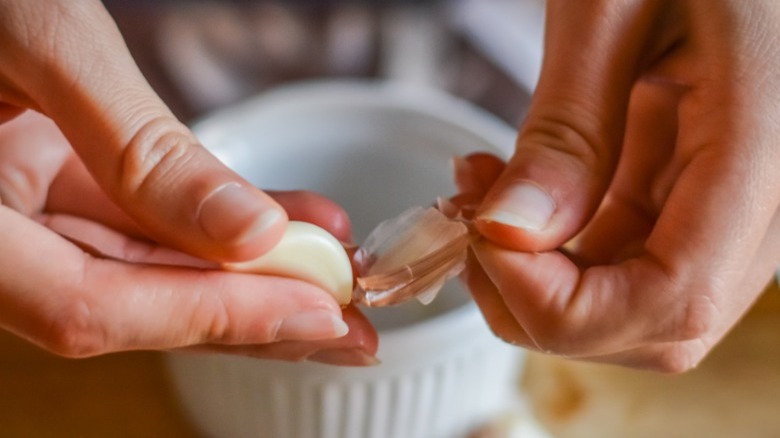 Hands peeling skin off garlic