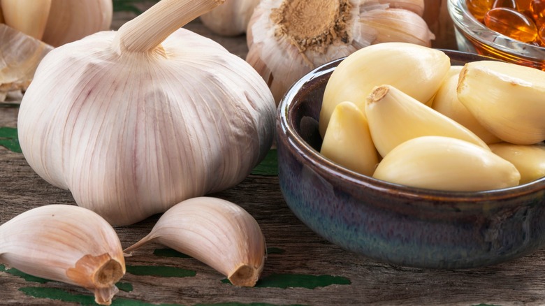 A garlic bulb with unpeeled gloves in a bowl on the side