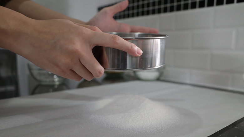 hands measuring out dry ingredients over a sheet of wax paper