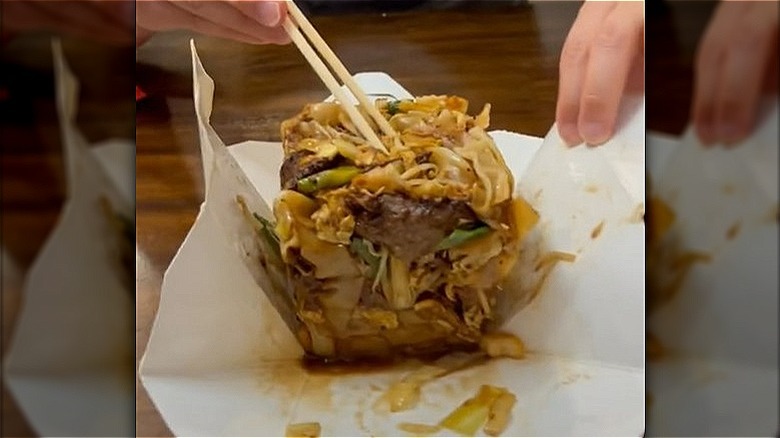 holding chopsticks while opening takeout box