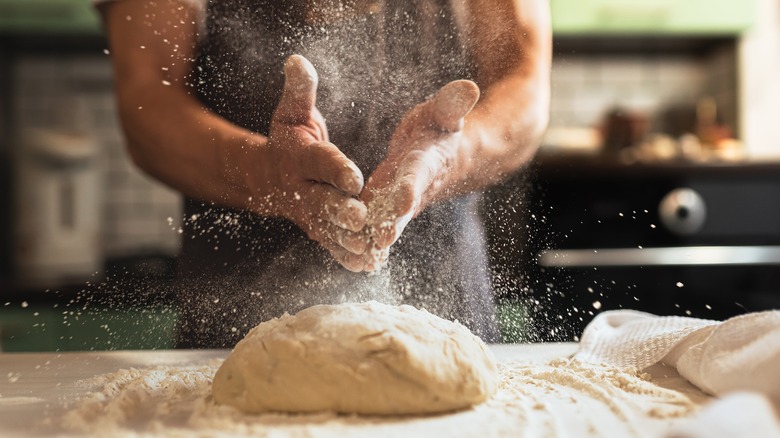 Person wearing apron kneading dough 