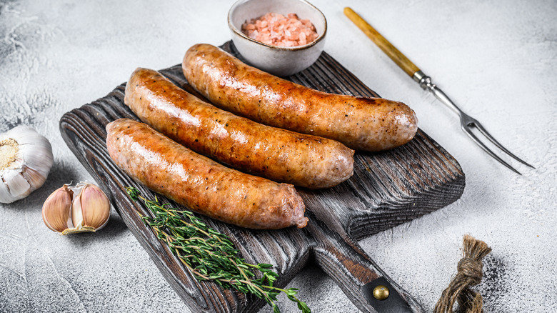 Three sausages sit on a cutting board