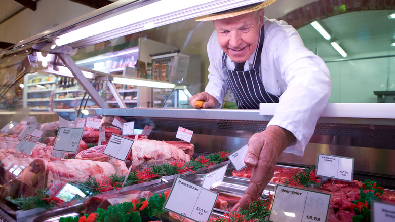 Butcher reaching for a cut of meat