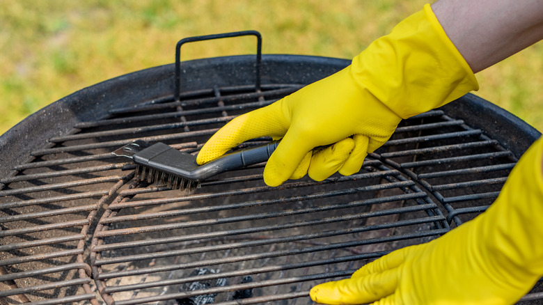 Rubber gloved hands cleaning grill