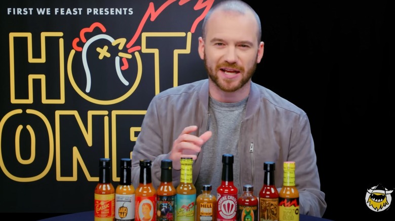 Sean Evans with bottles of hot sauce on Hot Ones