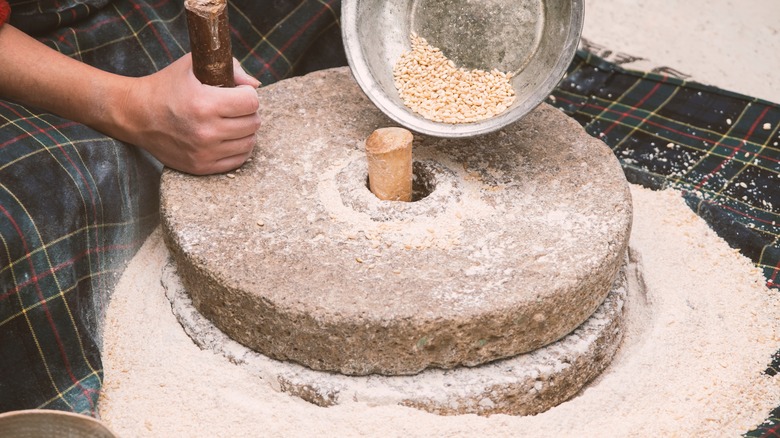 Person milling with quern