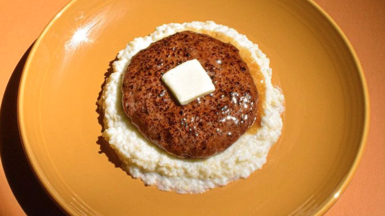 Salisbury steak with grits on yellow plate