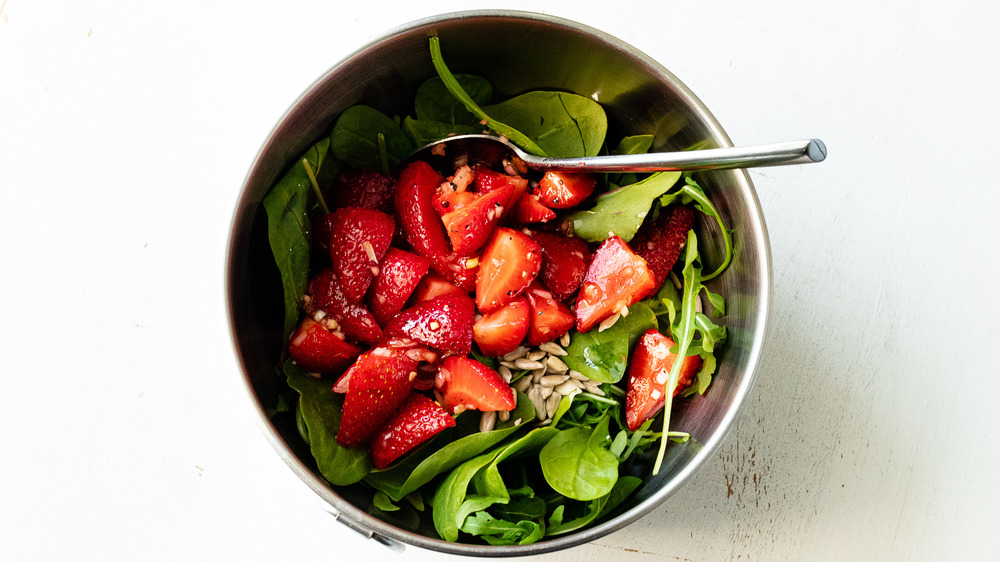 tossing strawberry spinach salad