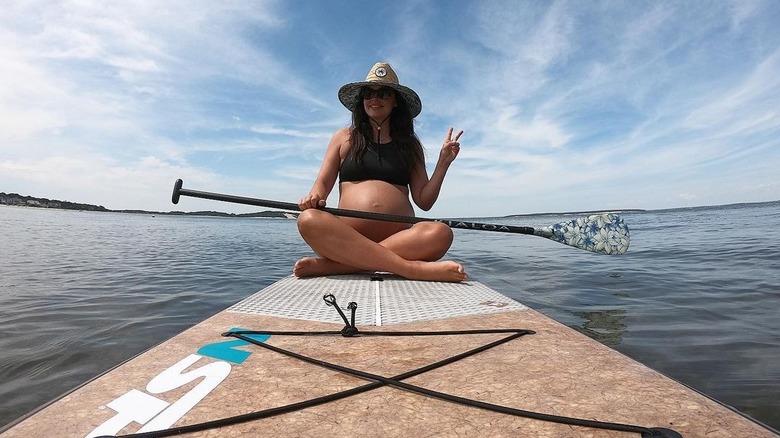 Katie Lee on paddle board giving peace sign