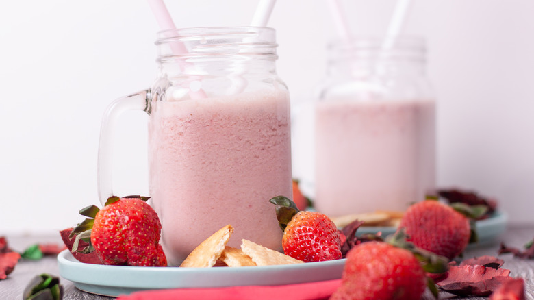 Strawberry milkshake with whole strawberries and biscuits on the side