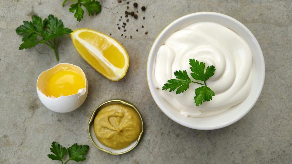 A bowl of mayonnaise set next to ingredients