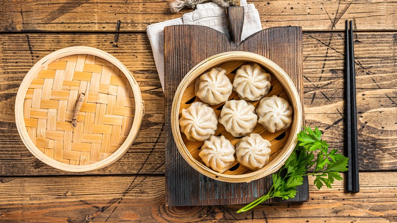 soup dumplings in steamer basket with chopsticks