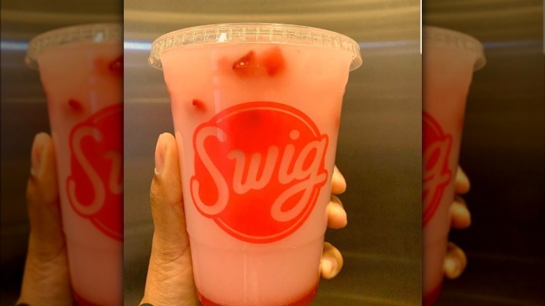 A person's hand holding a drink from Swig