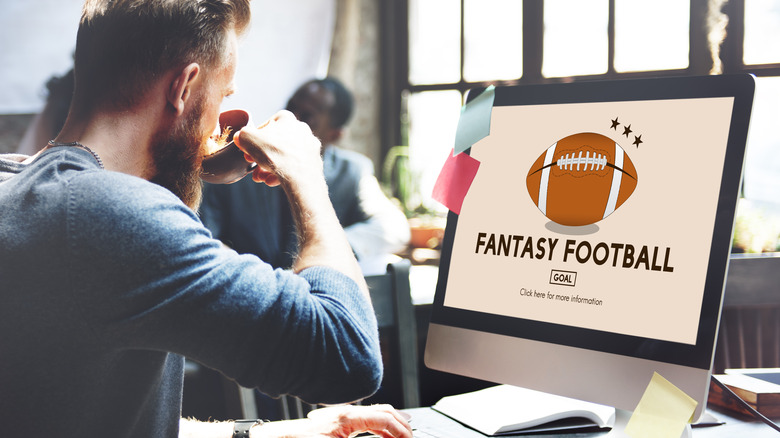 Man sitting in front of computer drinking coffee with Fantasy Football on screen