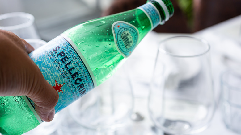 hand pouring a bottle of San Pellegrino