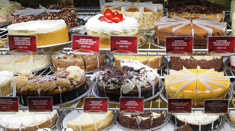 Three shelves of Cheesecake Factory cakes on display