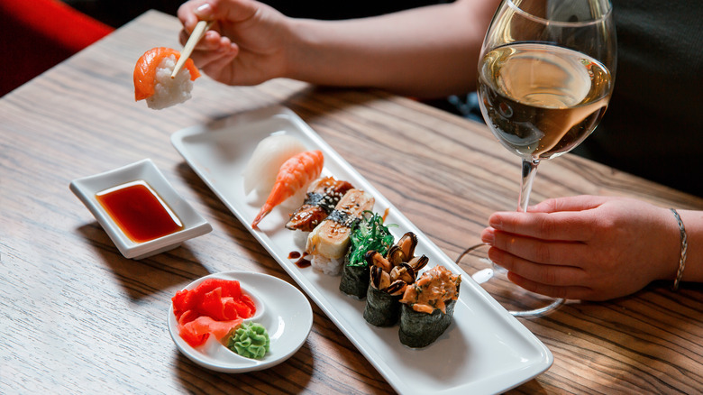 Person dipping nigiri sushi into soy sauce