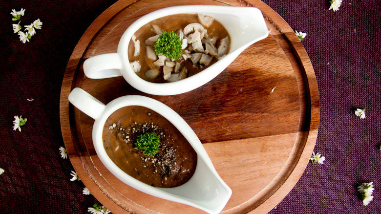 Two gravy boats on a wooden tray