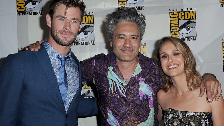 Chris Hemsworth, Taika Waititi, and Natalie Portman smiling on the red carpet