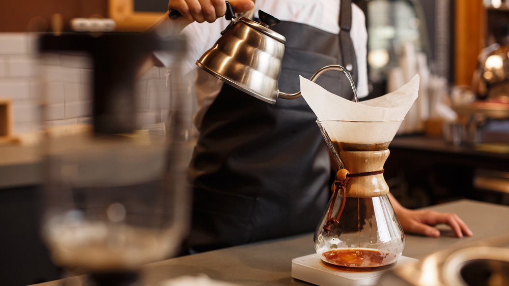 Person pouring hot water into coffee