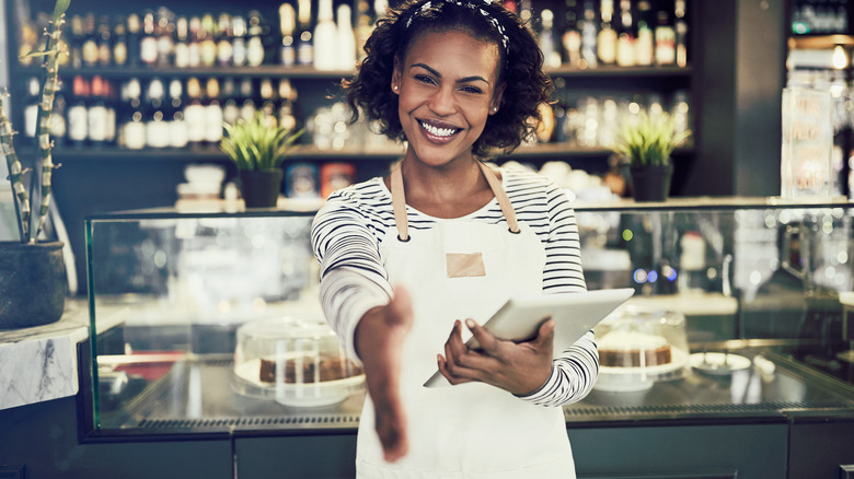 Server smiling and extending hand