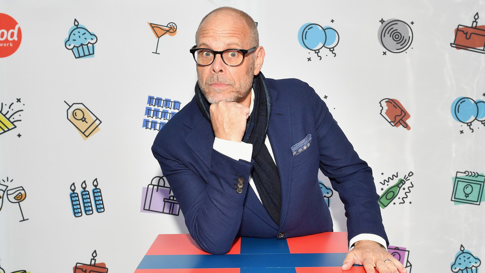 Alton Brown leaning on a present